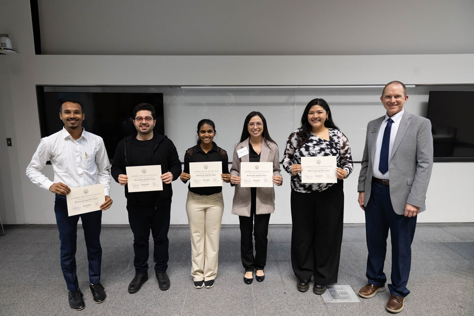 A group of students stand together and smiles with their awards.