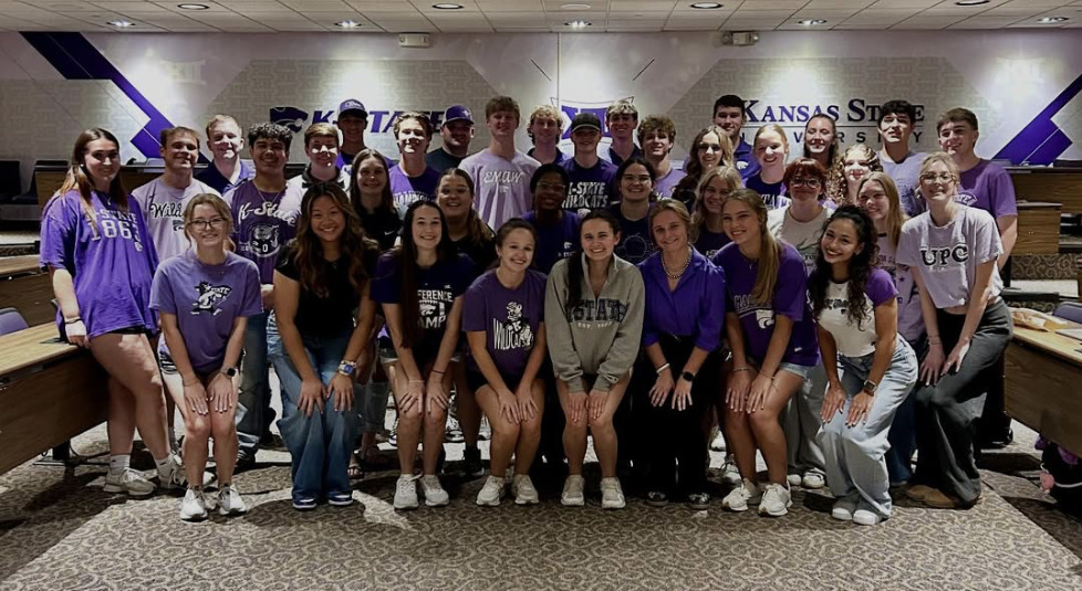 College students wearing various K-State apparel pose for a group photo.
